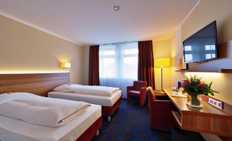 a modern hotel room with two beds , a window , and a desk , giving it a cozy and comfortable feel at Hotel am Dom