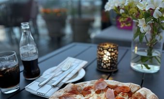 a pizza with ham and cheese on a dining table , accompanied by a bottle of soda at Quality Hotel Fredrikstad