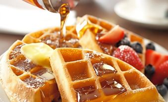 a plate of waffles topped with fruit and syrup is being poured onto a table at Country Inn & Suites by Radisson, Toledo, Oh