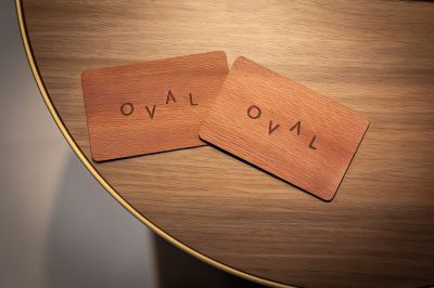 "two wooden business cards with the word "" oval "" engraved on them are placed on a wooden table" at Oval Hotel at Adelaide Oval, an EVT hotel