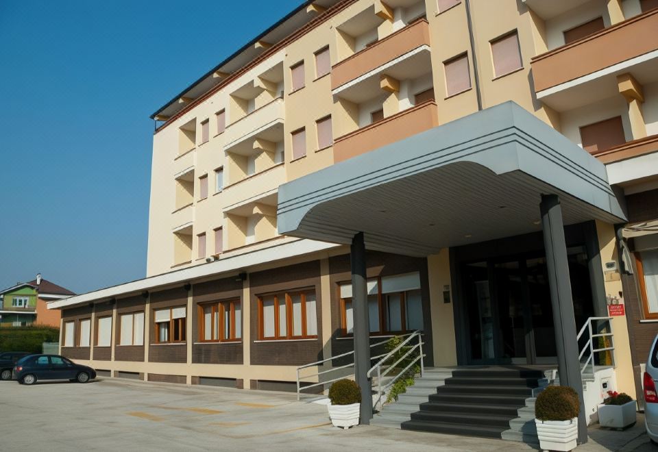 a modern hotel building with multiple balconies and windows , surrounded by trees and a parking lot at Hotel Touring