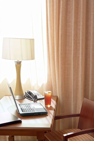 a desk with a laptop , phone , and candle next to a window with curtains , near a window with curtains at Country Inn & Suites by Radisson, Watertown, SD