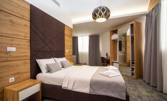 a large bed with white linens is in a room with wooden headboard and gray carpet at Hotel Grand