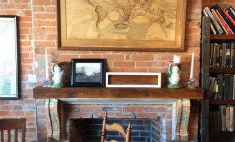 a brick fireplace with a framed map above it , along with a dining table and chairs at William Watson Hotel