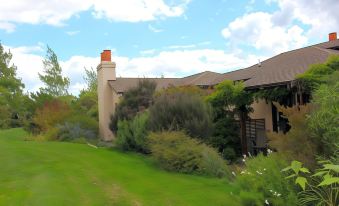 a house with a red chimney is surrounded by greenery and bushes , with a blue sky in the background at The Summit Lodge