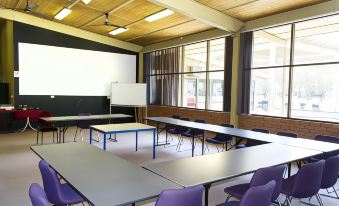 a large , empty conference room with multiple tables and chairs arranged in rows , under a high ceiling with wooden beams at Litchfield Outback Resort