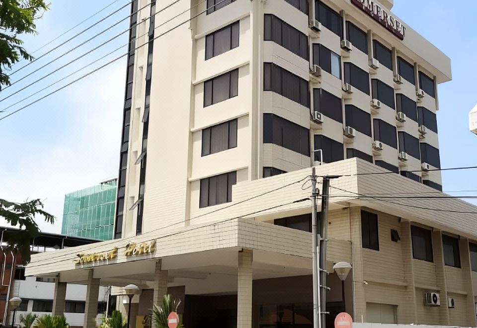 "a white building with a sign that reads "" hotel "" on it , situated in a city setting" at Somerset Hotel