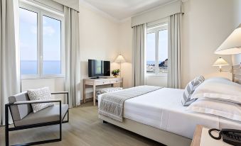 a modern hotel room with a large bed , white furniture , and a view of the ocean at Grand Hotel Arenzano