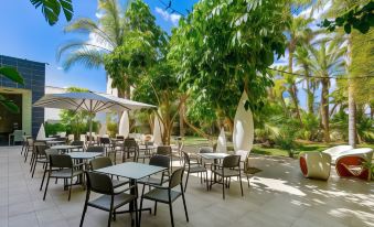 an outdoor dining area with tables and chairs arranged around a central pool , surrounded by lush greenery at Hotel Areca