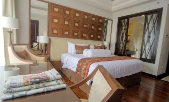 a large bed with white linens and a headboard is in a room with wooden floors at The Sunan Hotel Solo