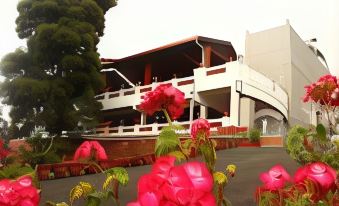 a building with a red roof and white walls is surrounded by flowers and bushes at Park Royale