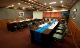 a conference room with a long table , chairs , and a projector screen in the background at Bay Hotel Srinakarin