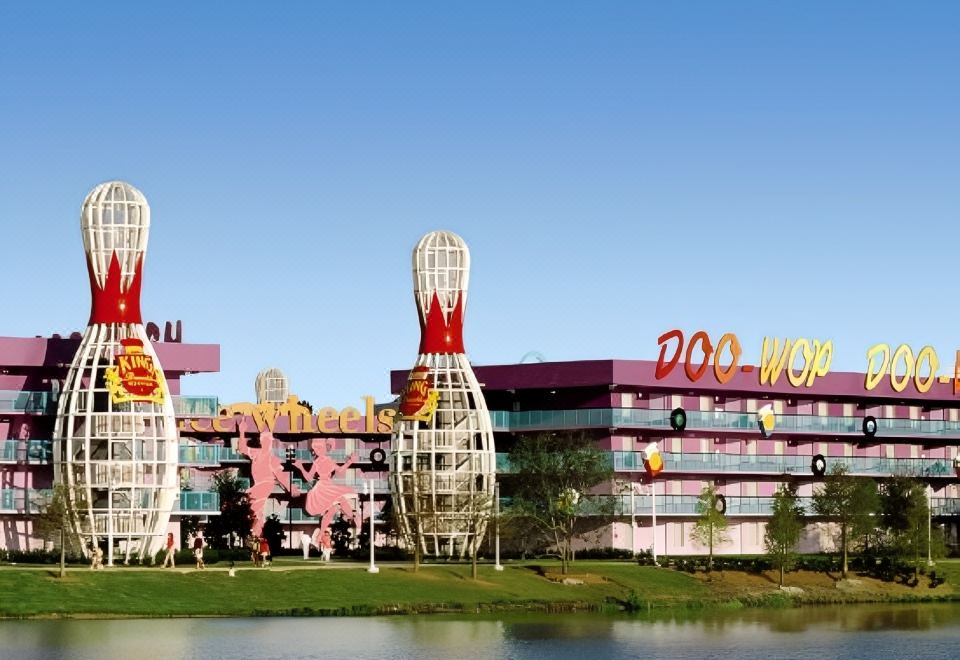 a large building with a red and purple exterior , possibly a hotel or an office building , situated near a body of water at Disney's Pop Century Resort - Classic Years