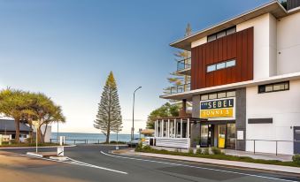 "a building with a yellow sign that says "" marina resort "" is next to a road" at The Sebel Brisbane Margate Beach