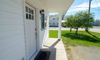 a white house with a porch , a door , and a car parked in the driveway at Colony Suites