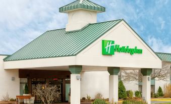 "a green and white hotel with a sign that reads "" holiday inn "" prominently displayed on the front" at Clarion Inn