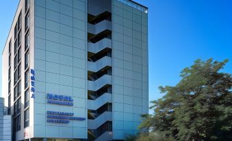 a tall , modern building with a blue and white exterior is located on a street corner at Hotel Ambassador