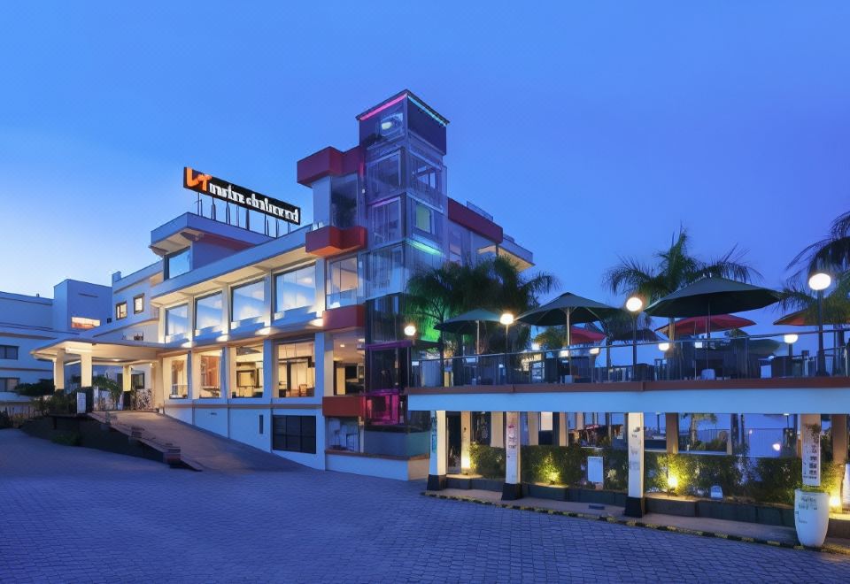 a modern building with a large glass facade and red windows , illuminated by lights at dusk at Swiss-Belhotel Silae Palu