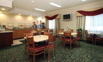 a dining area with several tables and chairs , a television mounted on the wall , and a buffet table at Country Inn & Suites by Radisson, Fairview Heights, IL