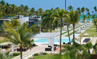 a large swimming pool surrounded by palm trees , with lounge chairs and umbrellas placed around the pool area at Small Luxury Hotels of the World - Sublime Samana Hotel & Residences
