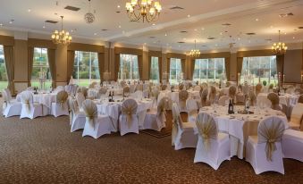 a large , well - decorated banquet hall with multiple tables and chairs set up for an event at Macdonald Craxton Wood Hotel