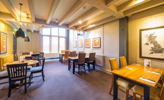 a dining room with wooden tables and chairs arranged for a group of people to sit and enjoy their meal at Crewe West