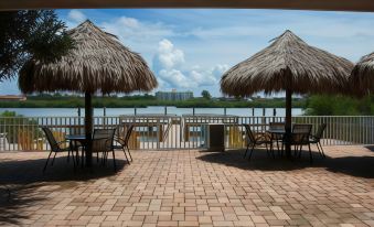 a patio area with two thatched - roof umbrellas and several chairs , overlooking a body of water at Legacy Vacation Resorts-Indian Shores