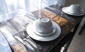 a dining table with a white plate , a fork , and a spoon on it , along with a napkin and other utensils at Seven Arches