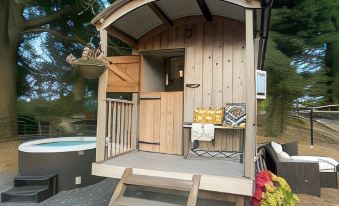 a small wooden house with a porch , surrounded by trees and a backyard with a hot tub at Hillcroft Accommodation