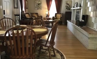 a spacious living room with wooden floors , large windows , and a dining area filled with chairs and tables at Sassafras Inn