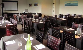 a large , well - lit room with multiple tables and chairs set up for a formal event at The Park Hotel Ruapehu