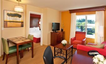 a hotel room with a bed , desk , and chair , as well as a living area with a couch and tv at Residence Inn Auburn