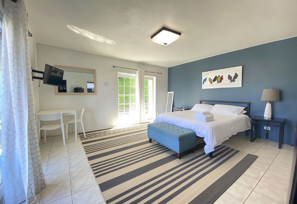 a bedroom with a bed , dining table , and chairs is shown with a striped rug at Seven Arches