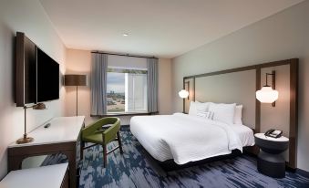 a large bed with white linens is in a room with a blue carpet and a chair at Fairfield by Marriott Edmonton International Airport