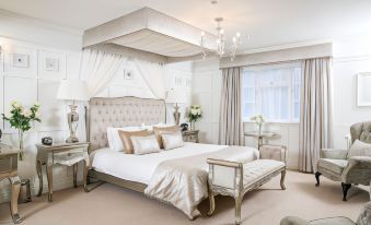 a luxurious bedroom with a large bed , white bedding , and elegant furniture , including a chandelier and nightstands at The Wild Boar