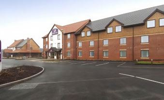 a large brick building with a purple logo on the side and a parking lot in front at Rugeley