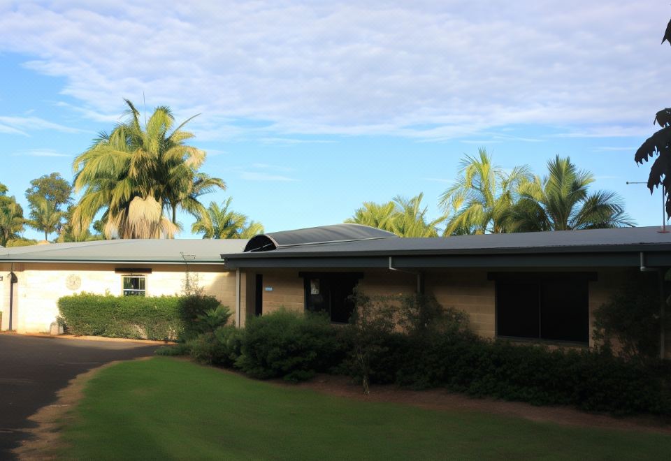 a house with a gray roof and white trim is surrounded by palm trees and greenery at Alstonville Country Cottages