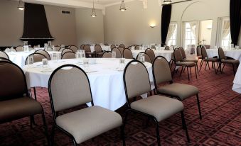 a large , empty banquet hall with multiple round tables and chairs set up for a formal event at Hanmer Springs Hotel