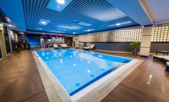 a large , empty swimming pool with blue water and white tiles , surrounded by wooden floors and walls at Hotel Holiday