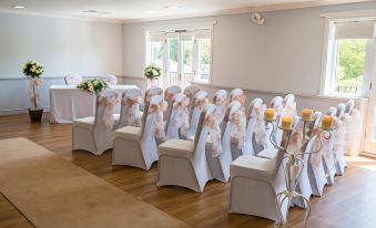 a room with rows of white chairs arranged for an event , each chair adorned with a pink bow at Macdonald Hill Valley Hotel Golf & Spa