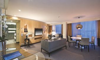 a modern living room with a gray couch , wooden paneling , and a large screen tv at Radisson Blu Waterfront Hotel, Stockholm