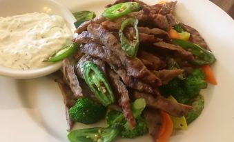 a plate of beef and broccoli with a side of ranch dressing on a wooden table at Cold Spring Hotel