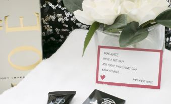 a bouquet of white flowers sits on a table next to two black containers and a card at Airport Hotel Sydney