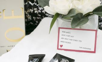 a vase with white flowers sits on a table next to two small black boxes at Airport Hotel Sydney