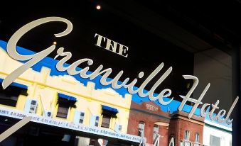 a large neon sign for the granville hotel is displayed above a building in a city setting at Granville Hotel
