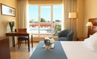 a hotel room with a large window overlooking a pool and a dining table set for breakfast at Hotel Albufera