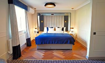 a large bed with a blue blanket is in a room with wooden floors and walls at Denham Grove