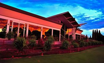 a modern building with a red facade and large windows , surrounded by green grass and trees at Renmark Country Club