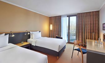 a hotel room with two beds , a chair , and a balcony , all decorated in a modern style at Lindner Hotel Leverkusen Bayarena