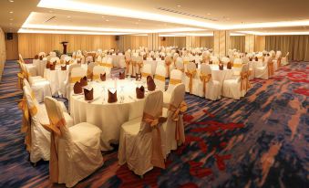 a large banquet hall filled with round tables and chairs , ready for a formal event at RHR Hotel Kajang